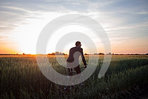 Portrait of stylish male with retro bicycle in summer wheat field