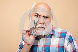 Portrait of stylish man bearded man with grey moustache beard hold barber scissors near face.