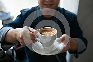 Portrait of stylish young man with cup of coffee.. Cappuchino or latte coffe in a white cup on a dark background. photo
