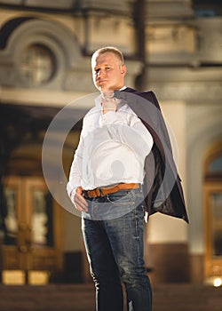 Portrait of stylish man on street holding jacket over shoulder