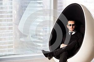 Portrait of stylish mysterious man in futuristic egg chair.