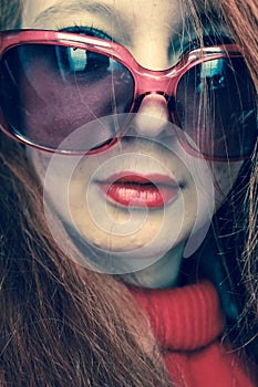 Portrait of a stylish sexy girl with red hair, red lipstick, in red glasses