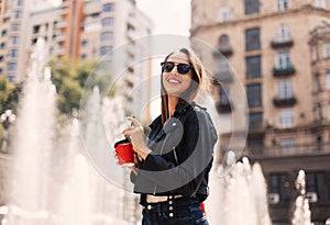 Portrait of stylish smiling happy woman walking in street with backpack.positive, emotional, long hair girl wearing black jacket,