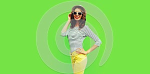Portrait of stylish smiling young woman model posing wearing striped t-shirt and summer straw round hat on green background, blank