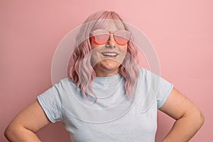 Portrait of stylish trendy woman in pink color glasses isolated over pink background