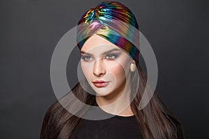 Portrait of stylish woman with long smooth straight hair and makeup in turban hat on black background