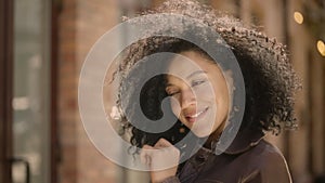 Portrait of stylish young African American woman flirtatious smiling and winking. Brunette in brown leather jacket