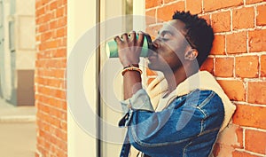 Portrait of stylish young african man drinking coffee on city street