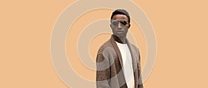 Portrait of stylish young african man model looking away wearing knitted cardigan isolated on brown background, blank copy space