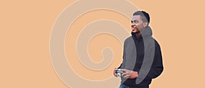 Portrait of stylish young african man photographer with film camera looking away wearing black hoodie isolated on brown background