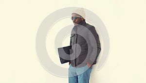 Portrait of stylish young african man posing wearing winter jacket with bag on white background