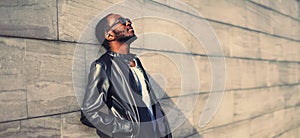 Portrait of stylish young african man wearing black rock leather jacket on city street background