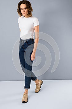 Portrait of stylish young girl in basic white t-shirt and high waisted blue jeans