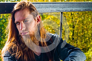 Portrait of stylish young man with beard and with long hair who
