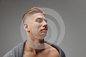 Portrait of stylish young man with blonde hair posing over grey studio background. Male beauty
