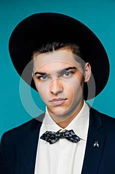 Portrait of a stylish young man in hat wearing elegant suit.