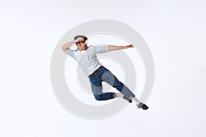 Portrait of stylish young man in retro outfit dancing, posing isolated over white studio background