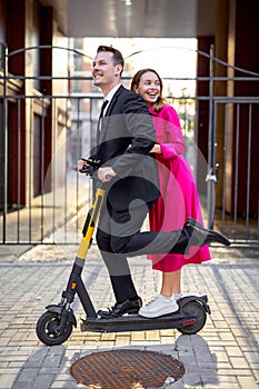 Portrait of stylish young people riding electric scooter in city street and smiling