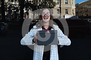 Portrait of stylish young woman with gift box in her hands. Happy smiling girl with box. Surprised face