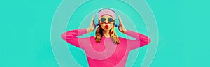 Portrait of stylish young woman in headphones listening to music blowing her lips sends sweet air kiss wearing colorful pink
