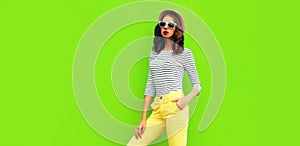 Portrait of stylish young woman model posing wearing striped t-shirt and summer straw round hat on green background, blank copy