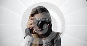 Portrait of a stylish young woman photographer in a white shirt with a pierced nose and long blond hair, making shots