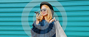 Portrait stylish young woman with shopping bags and phone using voice command recorder, assistant or takes calling in city