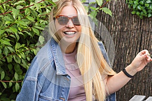 Portrait of stylish young woman in sunglasses with toothy smile. Happy blonde female wearing casual jean clothes.