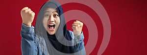 Portrait of success beautiful muslim businesswoman wearing hijab screaming shouting and shows winning victory gesture