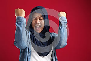 Portrait of success beautiful muslim businesswoman wearing hijab screaming shouting and shows winning victory gesture