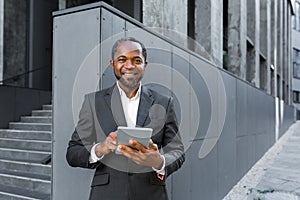 Portrait of a successful African American boss, a businessman in a suit smiling and looking at the camera, a man holding