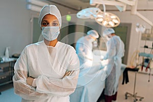 Portrait of successful African-American female nurse standing posing with crossed arms looking at camera in light