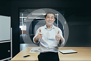 Portrét úspešný ázijský podnikateľ šéf muž stojace v kancelária najbližšie stôl pozerá na 