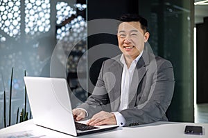 Portrait of successful asian businessman financier, man smiling and looking at camera, boss in business suit working