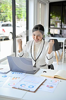 Portrait, Successful Asian businesswoman celebrating at her office desk. project winning