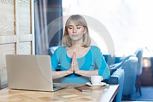 Portrait of successful attractive young girl freelancer in blue t-shirt are sitting in cafe and having a rest, holding hands like