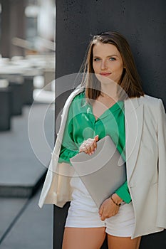 Portrait of successful brown-haired business woman with square haircut in fashionable suit with laptop in her hands.