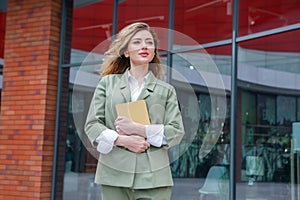 Portrait of a successful business woman in front of modern business building. Young manager poses outside.