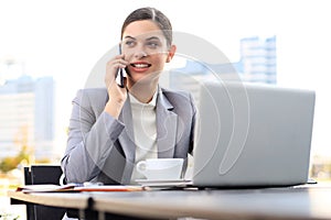 Portrait of successful business woman talking on the phone and smiling while working in the modern cafe