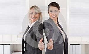 Portrait: Successful business woman team making thumbs up gesture.