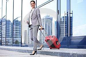 Portrait of successful business woman traveling with case at airport. Beautiful stylish female travel with luggage