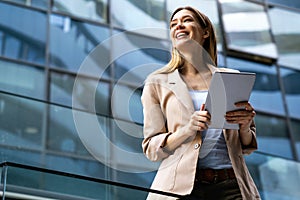 Portrait of a successful business woman using digital tablet in front of modern business building photo