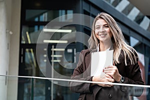 Portrait of a successful business woman using digital tablet in front of modern business office building. Professional female,