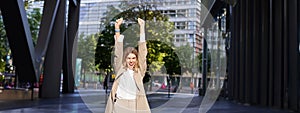 Portrait of successful business woman, young corporate woman celebrating victory, achievement, triumphing on street