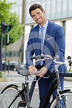 portrait successful businessman chaining bicycle