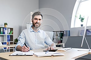 Portrait of a successful businessman man at paper work in the office, an accountant analyzes financial reports looks at the camera