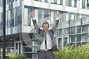 Portrait of successful businessman pointing upwards outside office