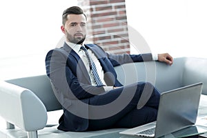 Portrait of a successful businessman sitting in the office lobby.