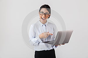 Portrait of successful businesswoman wearing eyeglasses holding silver laptop in the office, isolated over white background