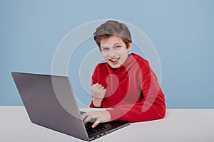 Portrait of successful child boy winner near the table